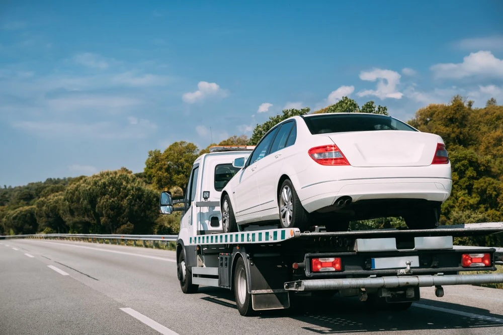 A car on the back of a recovery truck, being taken away